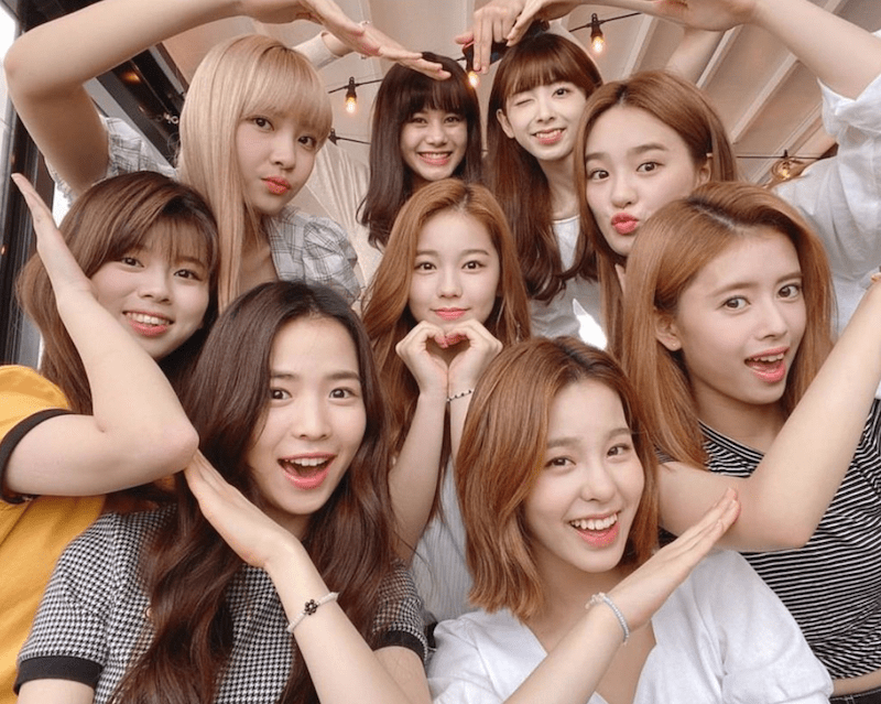 NiziU: Riku, Mayuka, Nina, Miihi, Rio, Rima, Mako, Maya e Ayaka fazem formato de coração com as mãos