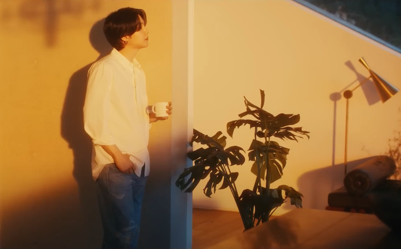 Suga do BTS pensativo com uma caneca de café na mão no MV da música People Pt. 2