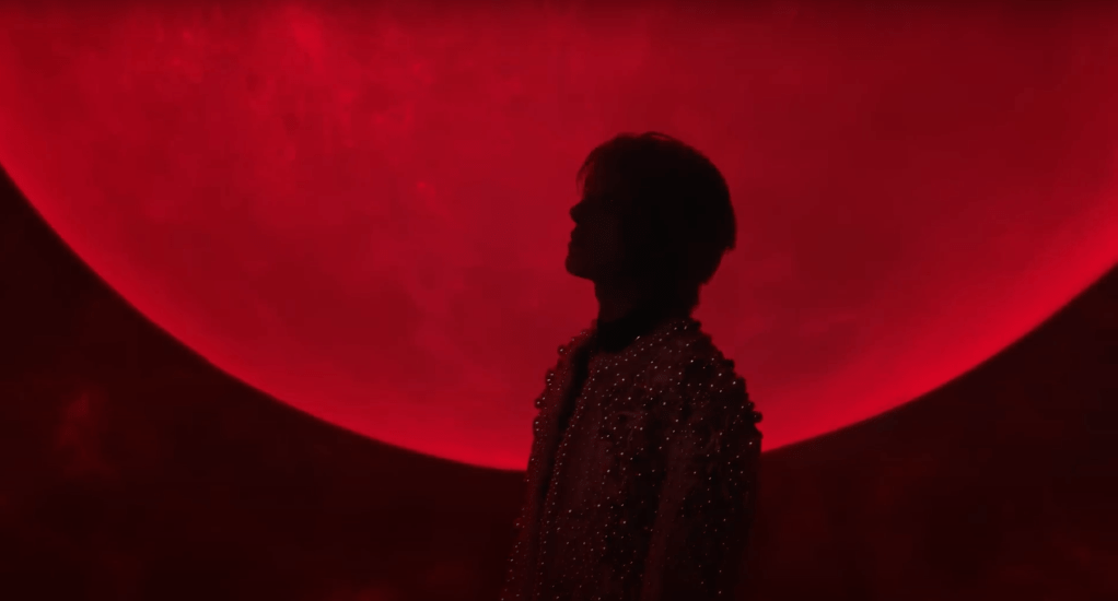 Cena do MV de Bite Me do álbum Dark Blood do ENHYPEN com silhueta e lua vermelha ao fundo