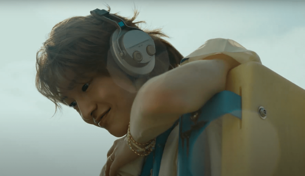 Cena do MV de The Feeling do SHINee com Onew usando fone de ouvido e sorrindo