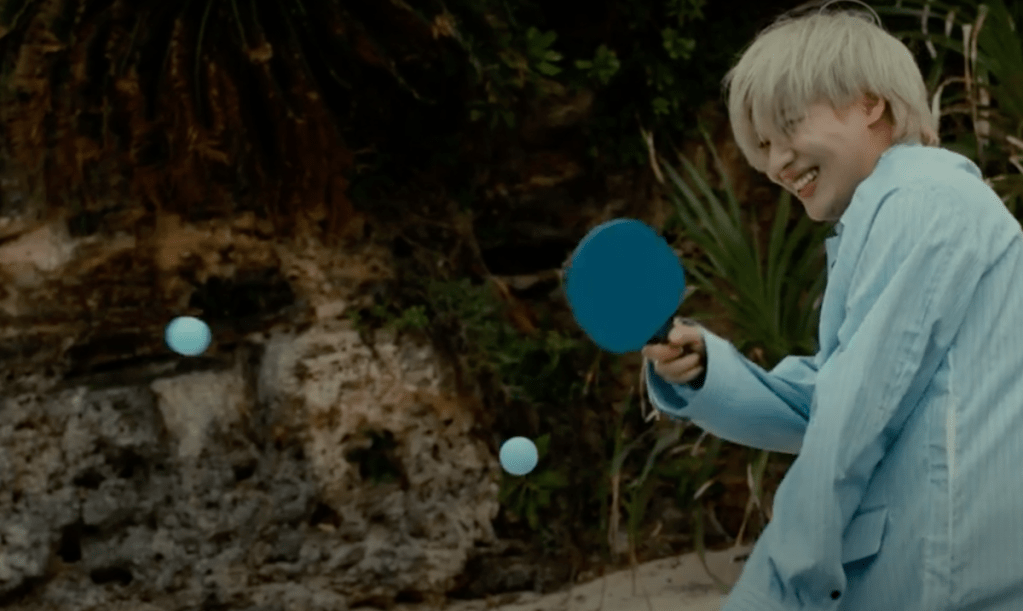 Cena do MV de The Feeling do SHINee com Taemin jogando pingue-pongue e sorrindo