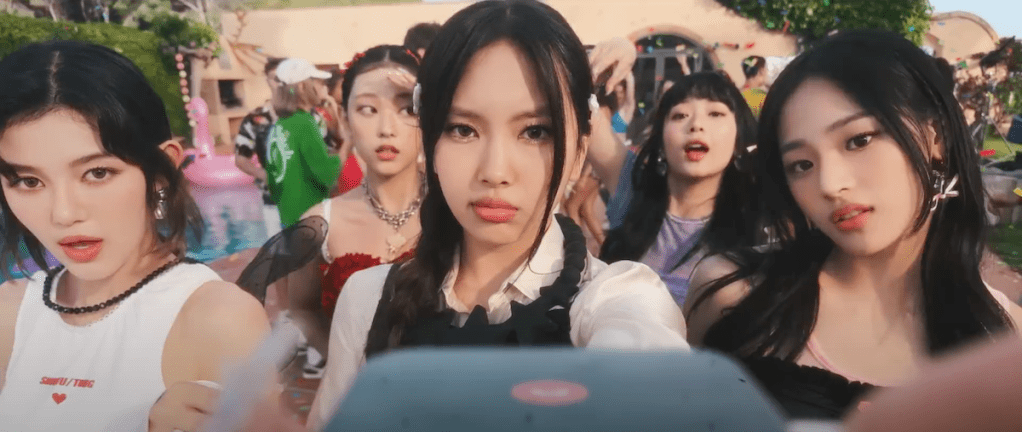 Cena do grupo NewJeans gravando vídeo com o celular para a música ETA do álbum Get Up