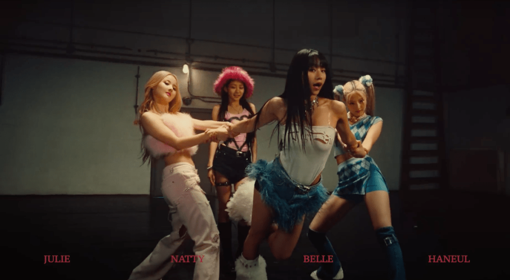 Cena do MV de Shhh, KISS OF LIFE, com Belle e Haneul segurando Natty e Julie no fundo