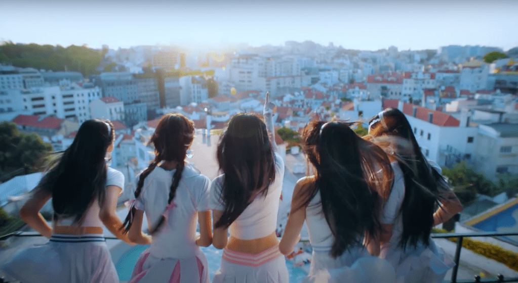 Cena do grupo NewJeans com vista de Portugal para a música Super Shy do álbum Get Up