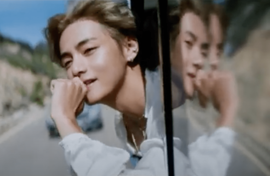 Cena do MV de "Slow Dancing" do álbum Layover do V com o rosto para fora da janela do carro