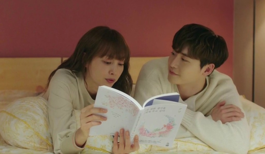 Cena de Romance is a Bonus Book com Cha Eun-Ho (Lee Jong-Suk) e Kang Dan-Yi (Lee Na-Young) deitados na cama lendo um livro