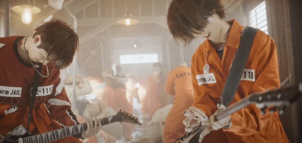Cena do MV de "Break the Brake" do álbum Livelock com Gaon e Jun Han da banda Xdinary Heroes tocando em um vagão de trem