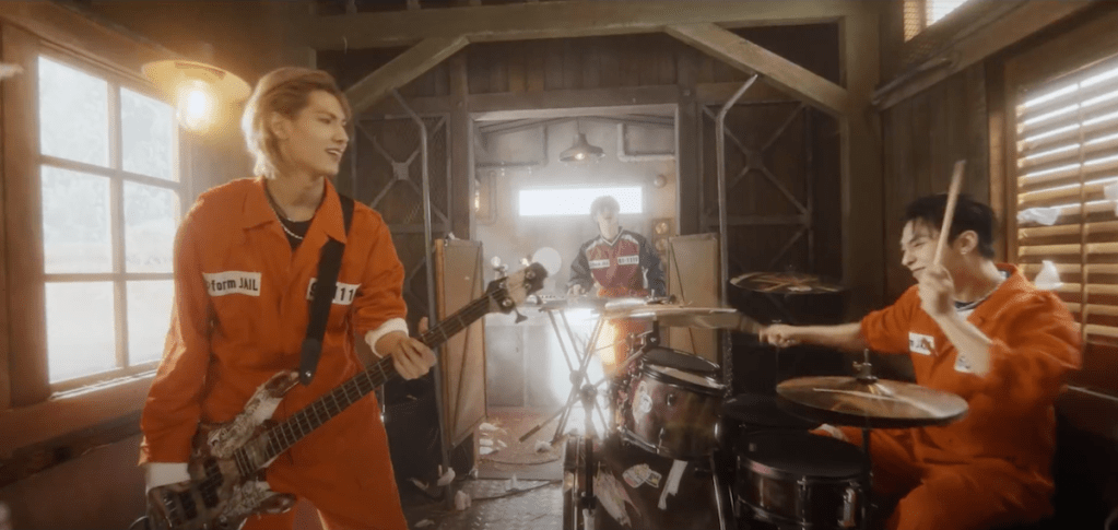 Cena do MV de "Break the Brake" do álbum Livelock com Jooyeon e Gunil da banda Xdinary Heroes tocando em um vagão de trem