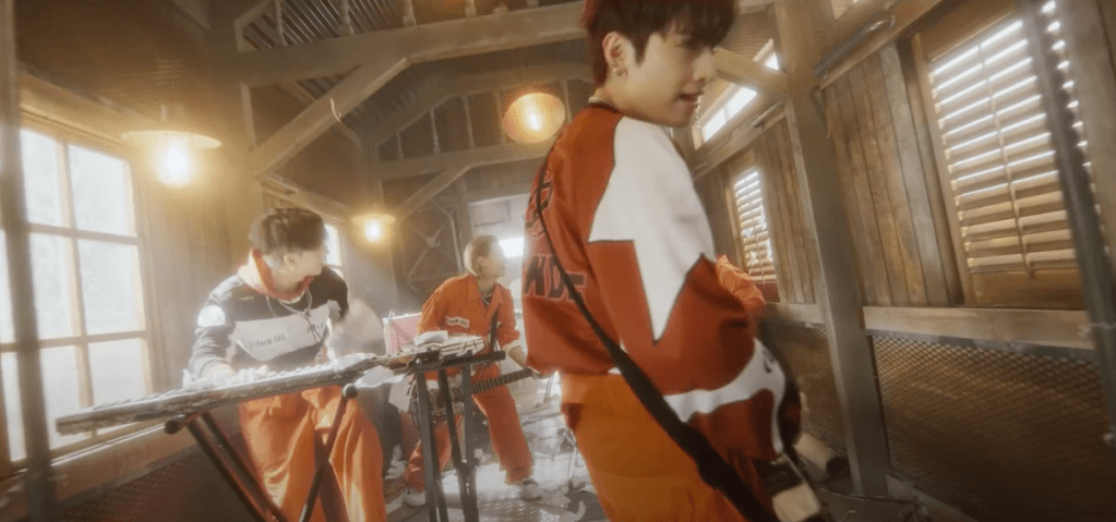 Cena do MV de "Break the Brake" do álbum Livelock com O.de da banda Xdinary Heroes tocando em um vagão de trem