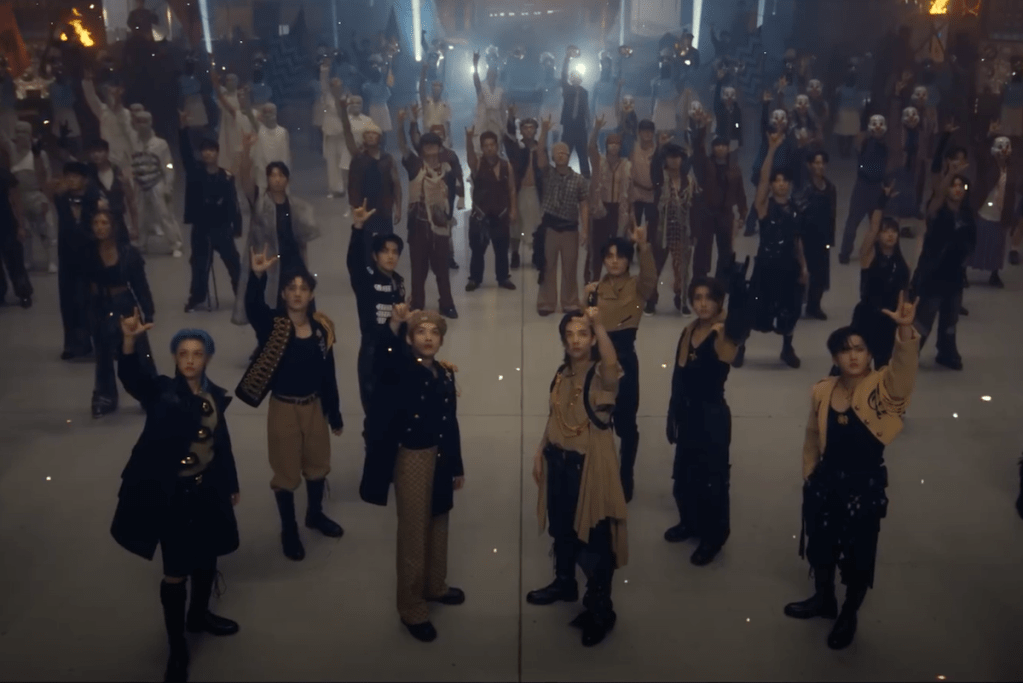 Cena do MV de "LALALA" do álbum 樂-STAR do Stray Kids com os meninos olhando para cima com o sinal de rock nas mãos e dançarinos ao fundo