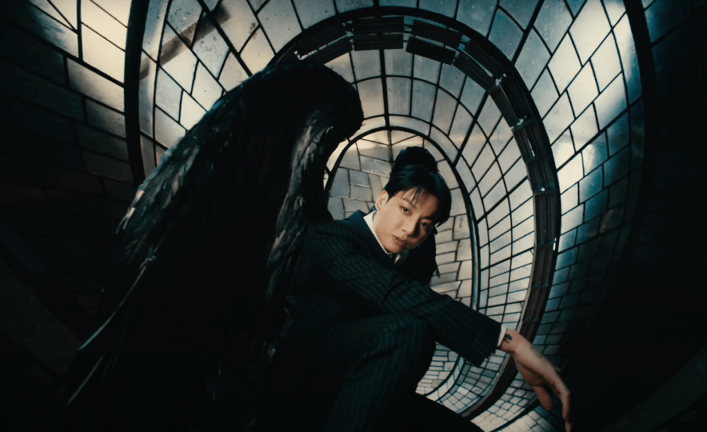 Cena do MV de "Standing Next to You" do album Golden com Jungkook usando asas pretas