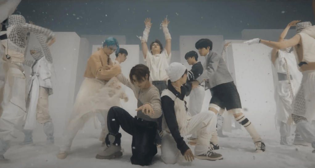 Cena do MV de "LALALA" do álbum 樂-STAR do Stray Kids com os meninos ao centro, cercados por dançarinos em um cenário branco
