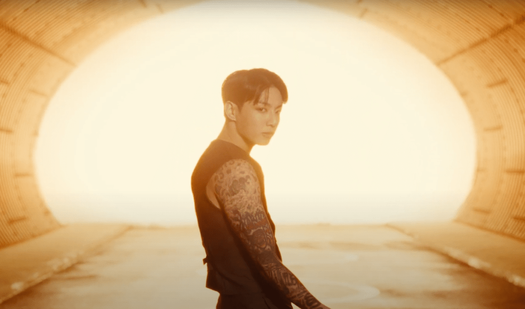 Cena do MV de "Standing Next to You" do album Golden com Jungkook em um túnel iluminado