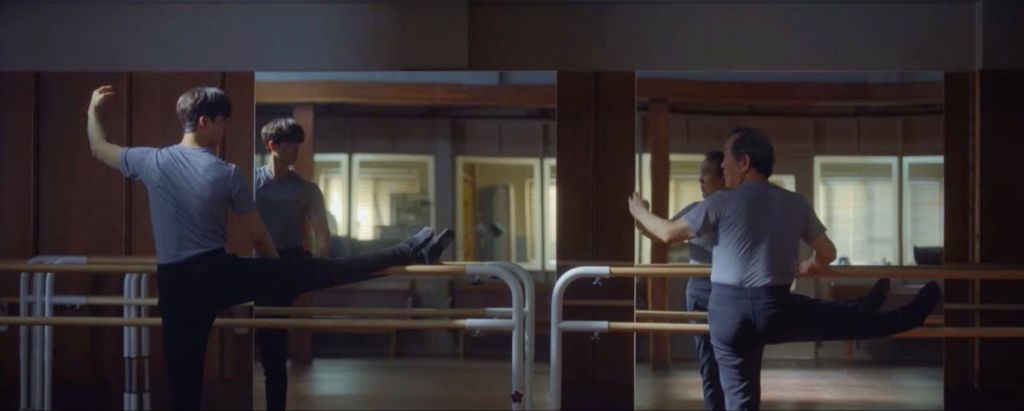 Cena do K-Drama Navillera com Deok-Chul e Chae-Rok ensaiando passos de balé na frente do espelho no estúdio de balé enquanto se olham