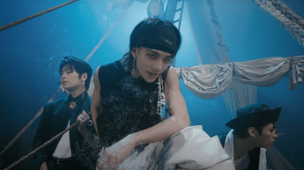 Cena do MV de "LALALA" do álbum 樂-STAR do Stray Kids com Hyunjin em foco a bordo de um navio