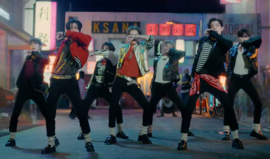 Cena do MV de "Sweet Venom", titletrack do álbum Orange Blood do ENHYPEN com o grupo no centro, dançando com as mãos no rosto
