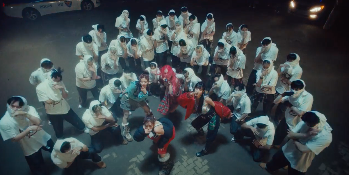 Cena do MV de "Bad News" do álbum Born to be XX do KISS OF LIFE com Haneul, Belle, Natty e Julie no centro dos dançarinos