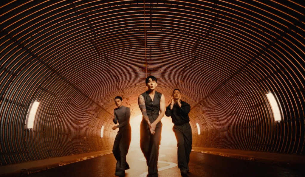 Cena do MV de "Standing Next to You" do album Golden com Jungkook em um túnel dançando ao lado de dois dançarinos