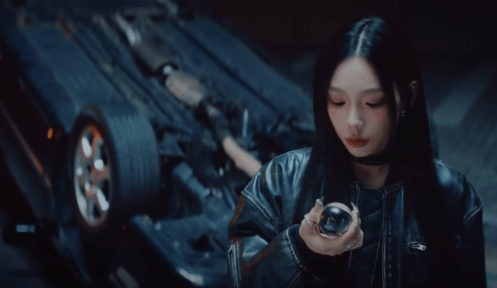 Cena do MV de "To. X" do álbum To. X com Taeyeon segurando uma pequena bola de vidro enquanto olha para ela e, ao fundo, um carro capotado