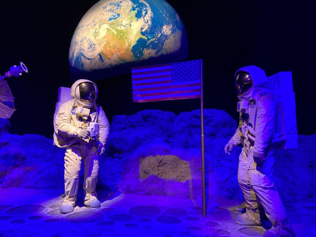 Astronautas na lua com bandeira dos EUA no centro em exibição no Museu da Nasa em Canela