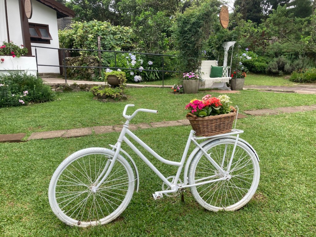 Bicicleta branca com cesto de flores no jardim da Casa da Dona Ivonne no Pé da Cascata do Caracol