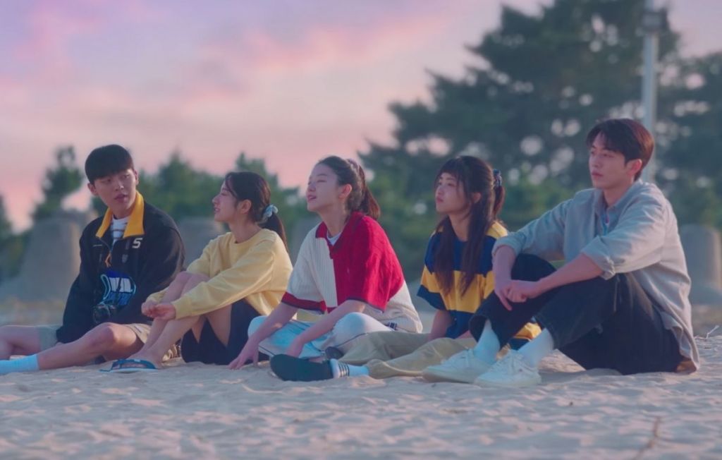 Cena de Twenty Five Twenty One na praia com o grupo de amigos sentados na areia