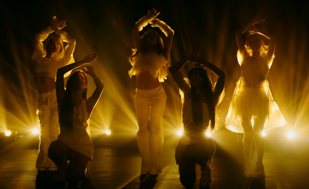 Andamiro, Mika, Sion, Yeyoung e Zoe dançando no MV de Voyage para o debut do Geenius, apenas as silhuetas aparecendo