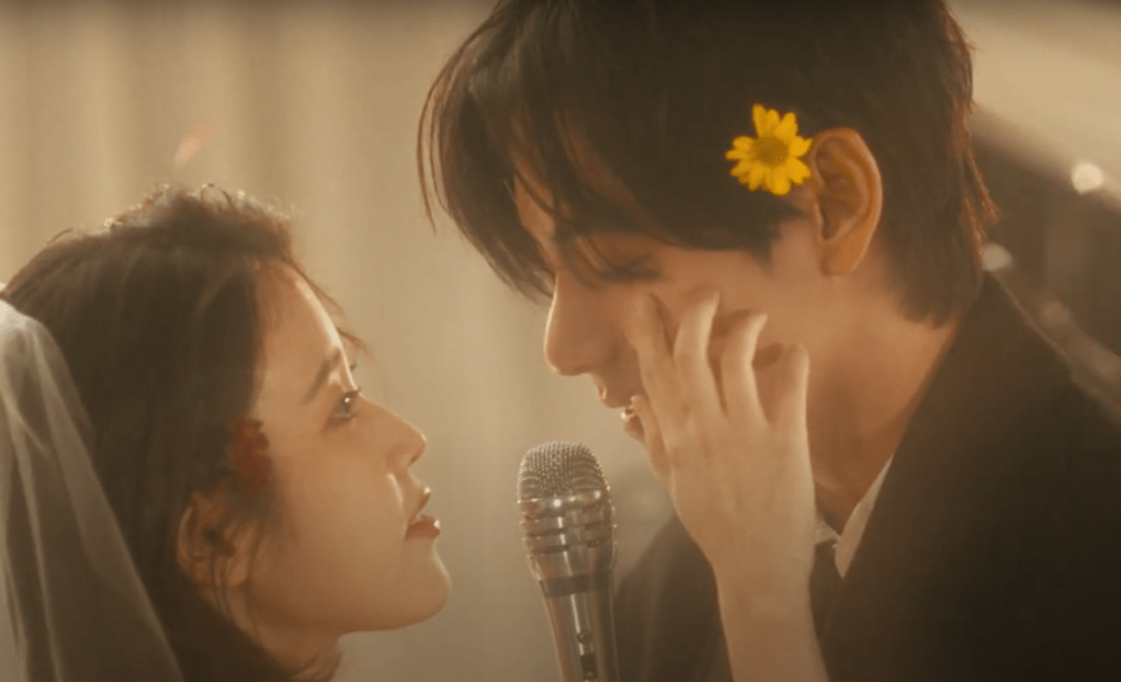 Cena do MV do single "Love wins all" com IU colocando a mão no rosto do V