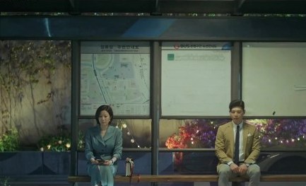 Cena do K-Drama Search: WWW com Ga-Gyung e Oh Jin Woo sentados lado a lado em uma parada de ônibus