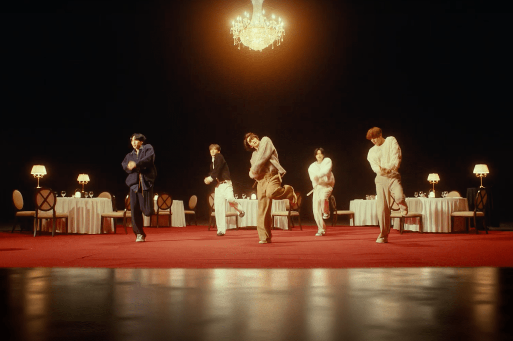 Cena do MV de "Lovers or Enemies" do álbum 0 or 1 do CIX, com os membros dançando em um cenário cheio de mesas com taças e abajures