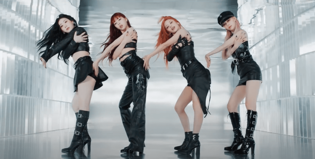 Cena do MV de UNTOUCHABLE do álbum Born to Be com as meninas do Itzy — Chaeryeong, Yuna, Ryujin e Yeji — dançando em um fundo branco enquanto olham para a câmera