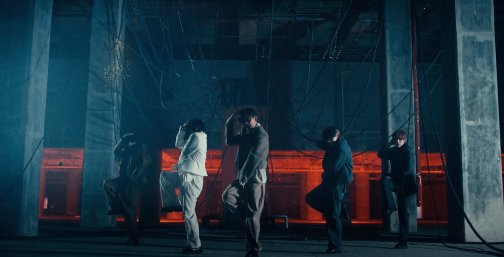 Cena do MV de "Lovers or Enemies" do álbum 0 or 1 do CIX, com a silueta dos membros dançando em um fundo escuro