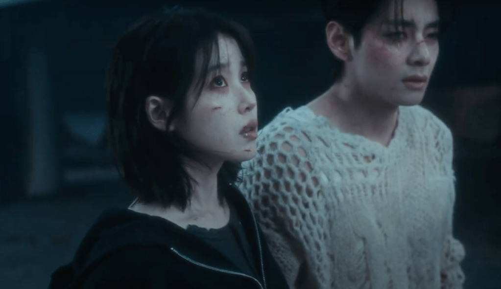 Cena do MV do single "Love wins all" com IU ao lado de V, os dois com expressões tristes