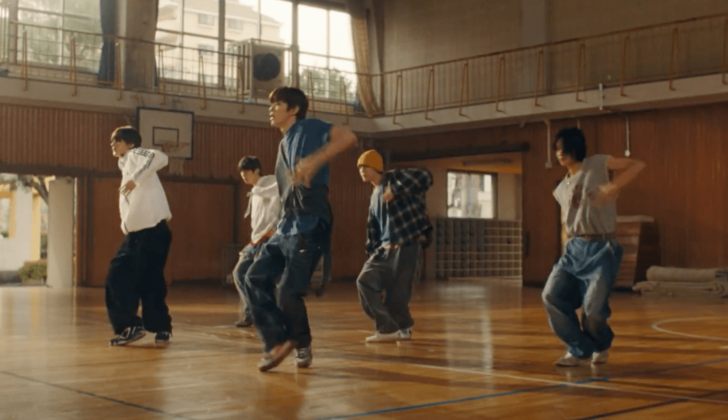 Membros do RIIZE no metrô dançando no ginásio em cena do MV de Love 119