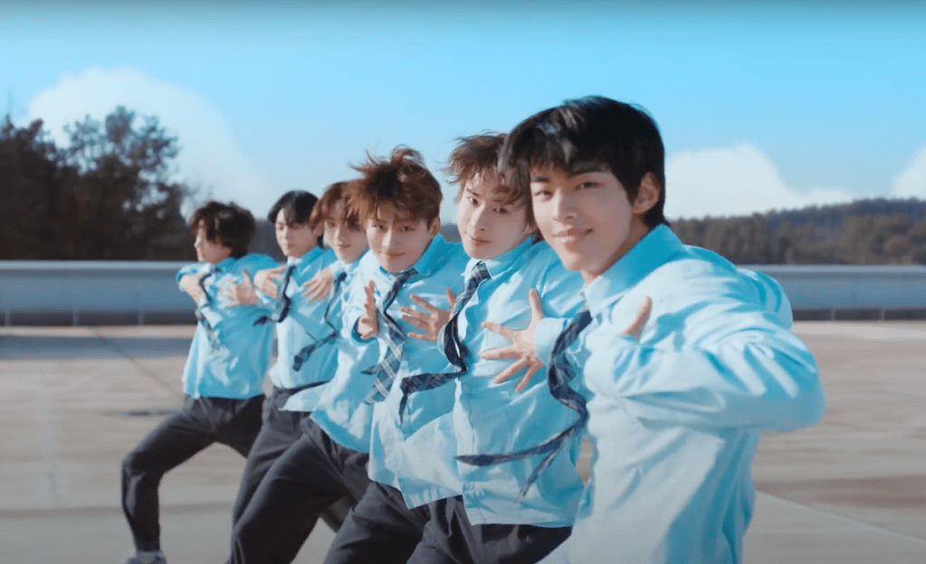 Cena do MV de "plot twist" do album Sparkling Blue com os meninos do TWS de uniforme dançando ao ar livre em fileira