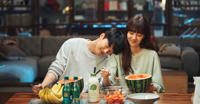 Cena do K-Drama Search: WWW com Mo-Gun se apoiando no ombro da Ta-Mi e uma mesa cheia de comida