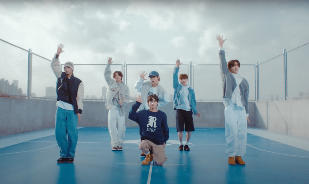 Cena do MV de "plot twist" do album Sparkling Blue com os meninos do TWS ao ar livre com as mãos para cima