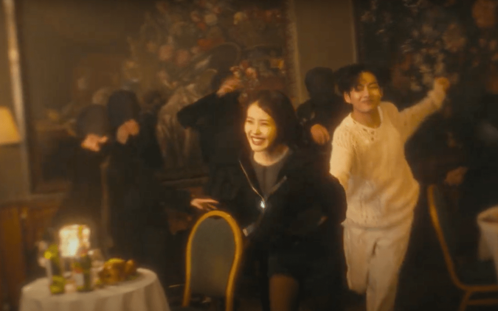 Cena do MV do single "Love wins all" com IU correndo de mãos dadas com V, os dois sorrindo