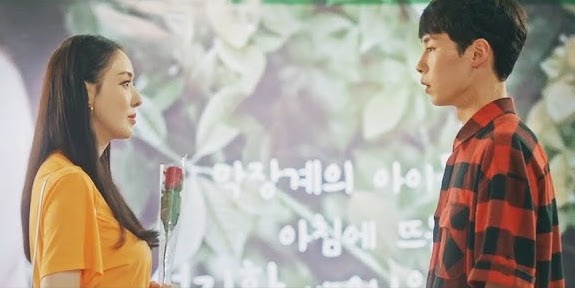 Cena do K-Drama Search: WWW com Scarlett olhando para o Ji-Hwan, enquanto segura uma rosa vermelha