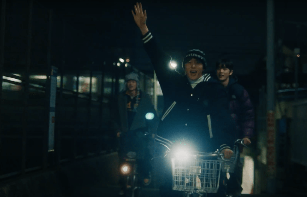 Membros do RIIZE no metrô andando de bicicleta de noite, em cena do MV de Love 119