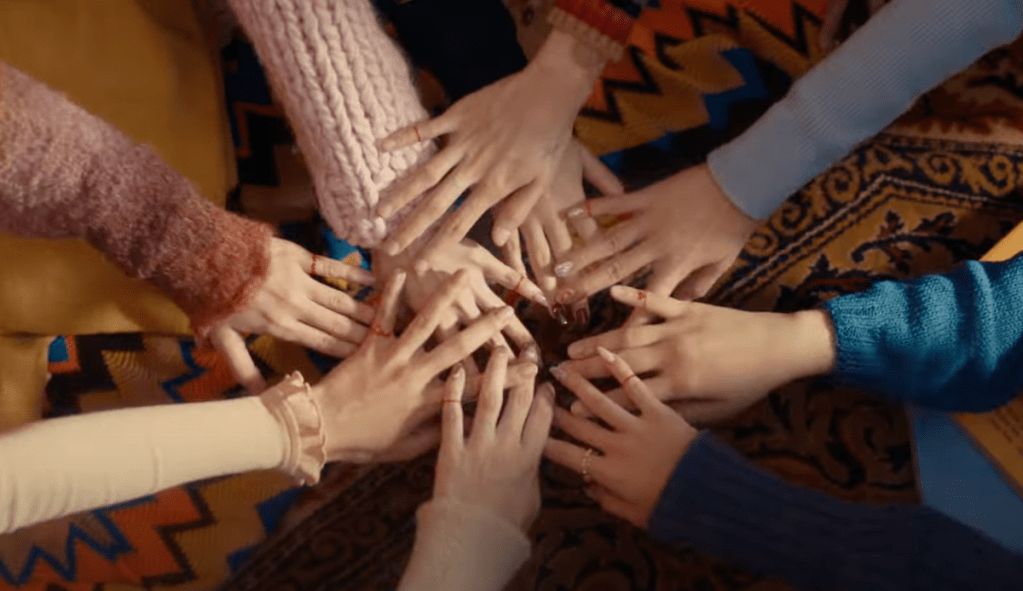 Mãos de todas as integrantes do TWICE unidas, uma em cima da outra, em cena do MV de "I Got You"