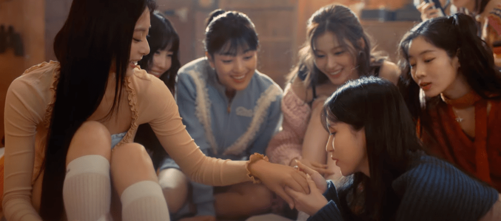 Cena do MV de "I Got You" do TWICE com Mina cuidando das unhas da Tzuyu, enquanto Momo, Jihyo, Sana e Dahyun acompanham 