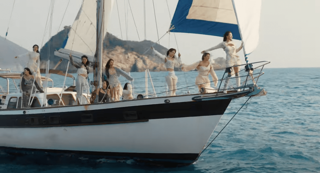 Cena do MV de "I Got You" do TWICE com as meninas velejando em um barco com o mar tranquilo