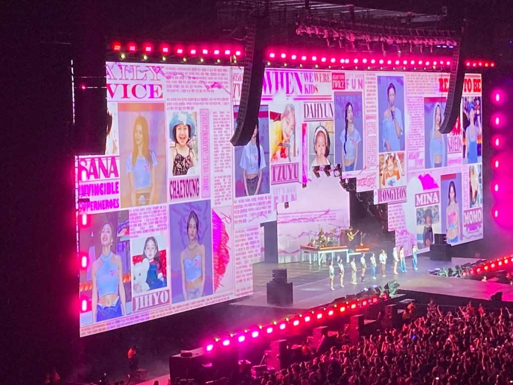 Show do TWICE no Brasil com imagem do palco. No telão, fotos das integrantes crianças se mesclam com imagens delas durante a apresentação no Allianz Parque em SP
