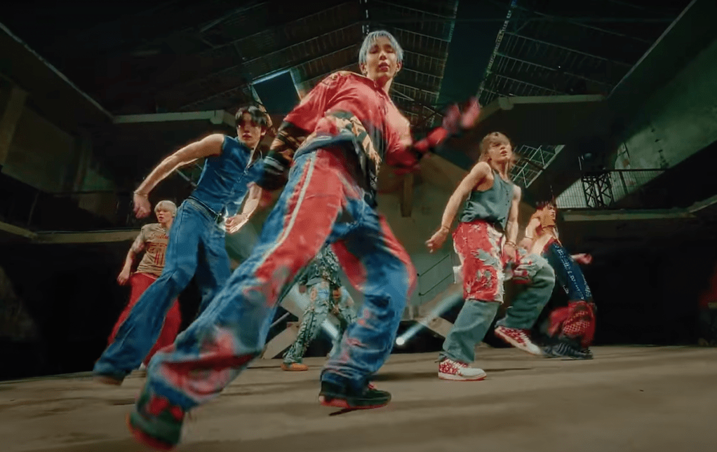 Cena de Anton, Eunseok, Sungchan, Shotaro, Sohee e Wonbin do RIIZE dançando no MV do single "Impossible" em um pavilhão