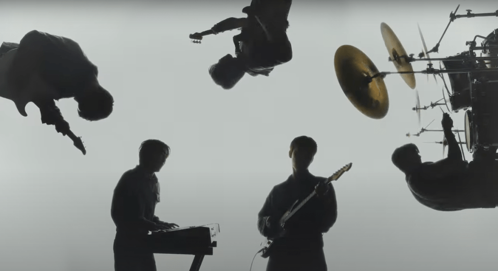 Silhuetas dos membros Dongmyeong, Giuk, Harin, Kanghyun e Yonghoon da banda ONEWE no MV de "Beautiful Ashes" do álbum Planet Nine: ISOTROPY
