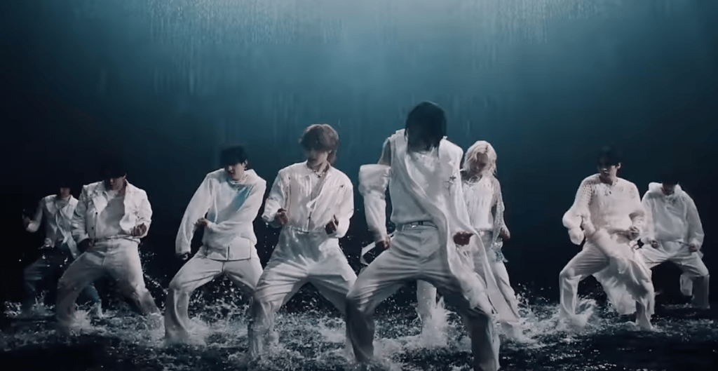 Trecho do MV de "Lose My Breath" do Stray Kids com Charlie Puth em cena de dança em um chão molhado, com todos vestindo branco