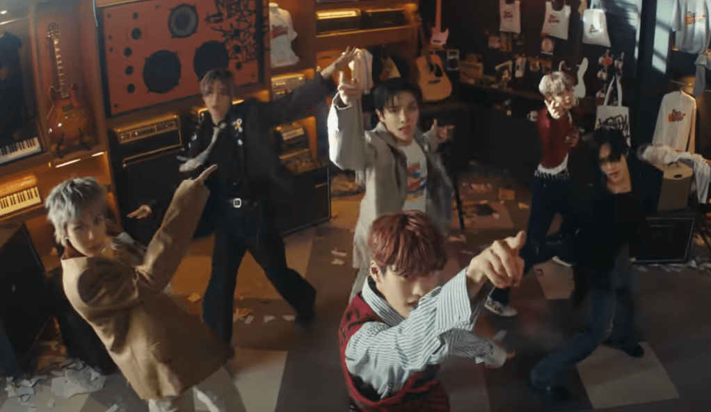 Cena do MV de "Boom Boom Bass" do álbum RIIZING com todos os membros do RIIZE dançando em uma sala cheia de instrumentos musicais