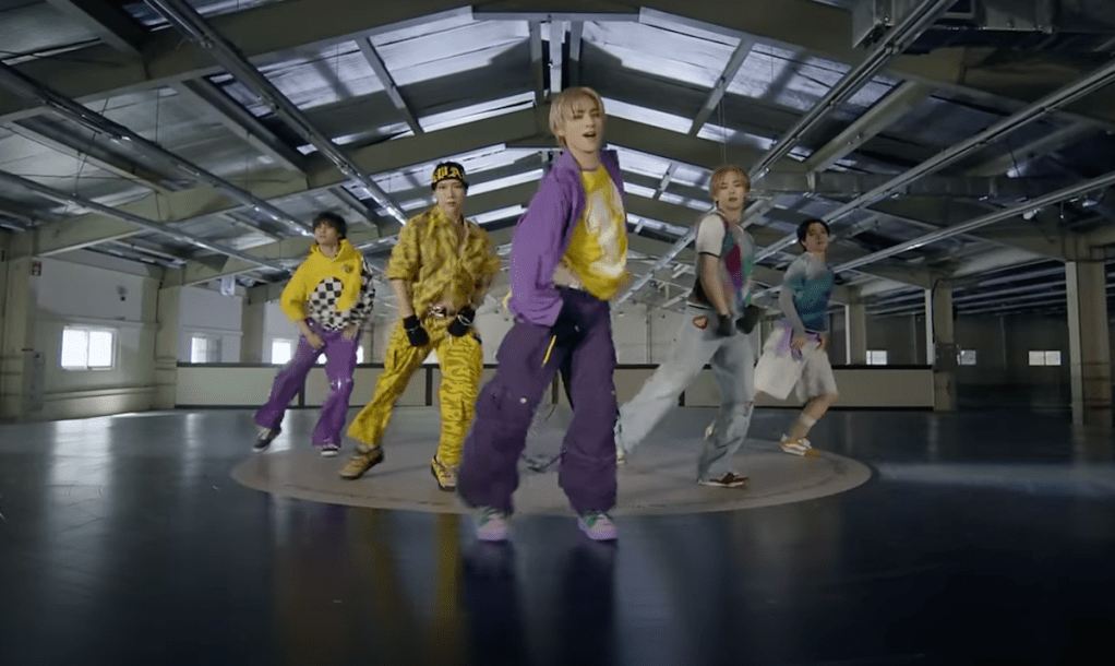 Cena do MV de "Give Me That" com os membros do WayV dançando em cima de um grande disco de vinil