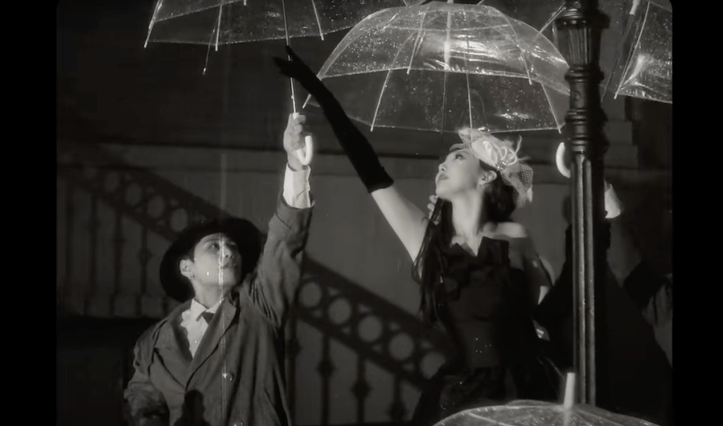 Cena do MV da música ABCD do álbum NA da Nayeon em primeiro comeback solo. Ela tenta alcançar uma sombrinha transparente em um cenário preto e branco, parecendo filme antigo